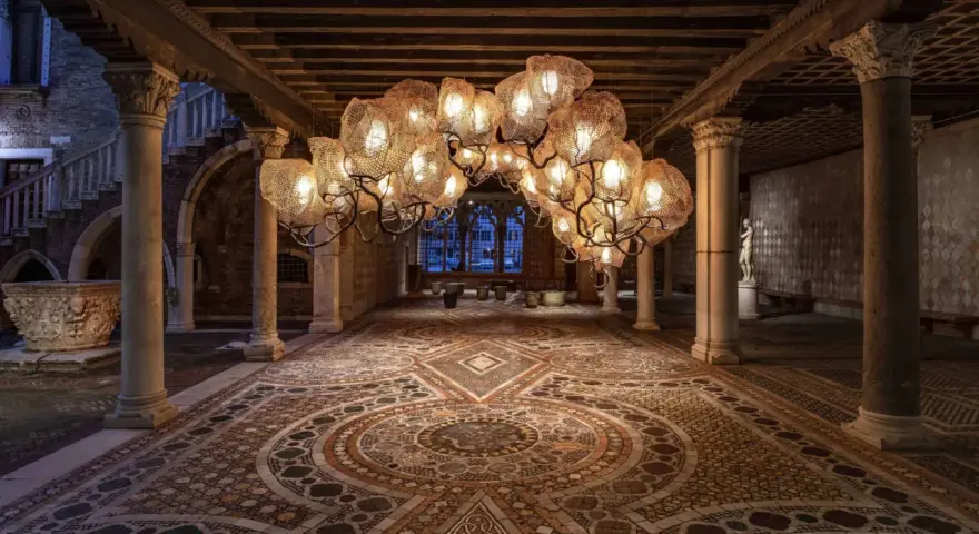 Interni Ca' d'Oro: un lampadario scenografico illumina il cortile con pavimenti a mosaico e colonne antiche.