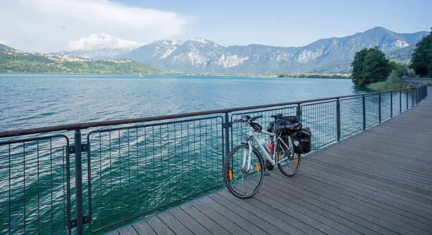Bicicletta da turismo pronta per esplorare le ciclabili Dolomiti, con un lago azzurro e montagne maestose sullo sfondo.
