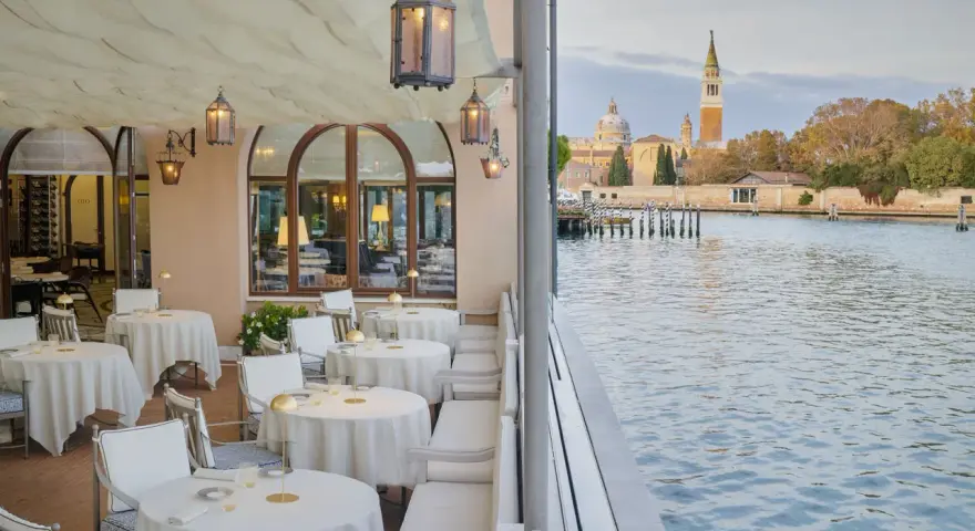 Terrazza elegante di uno dei ristoranti famosi a Venezia, con tavoli apparecchiati e vista sul canale e sulla città.