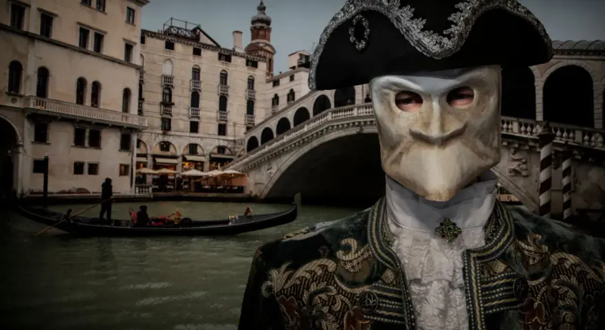 Un uomo mascherato, forse un Casanova a Venezia, con gondola e ponte sullo sfondo.