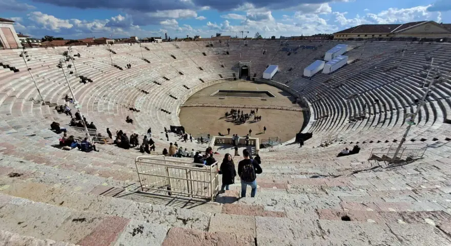 L'**arena di Verona colosseo** romano, con le sue gradinate affollate di turisti, sotto un cielo azzurro e nuvoloso.