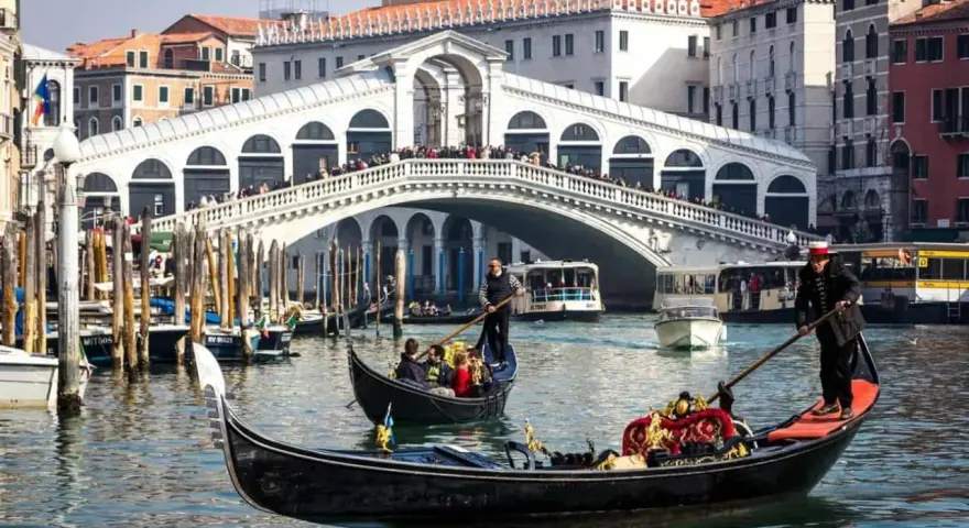 La gondola veneziana scivola sull'acqua, con il Ponte di Rialto sullo sfondo, un'icona di Venezia.