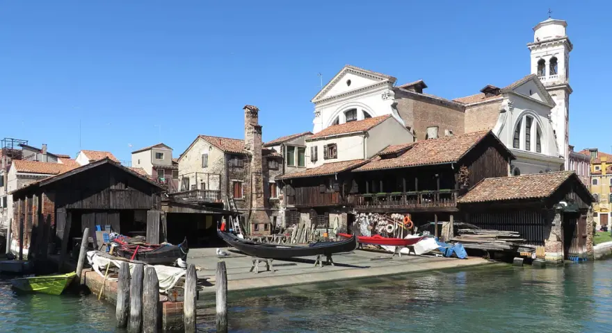 Lo squero di San Trovaso, con gondole in lavorazione e un campanile sullo sfondo, riflette la tradizione veneziana.
