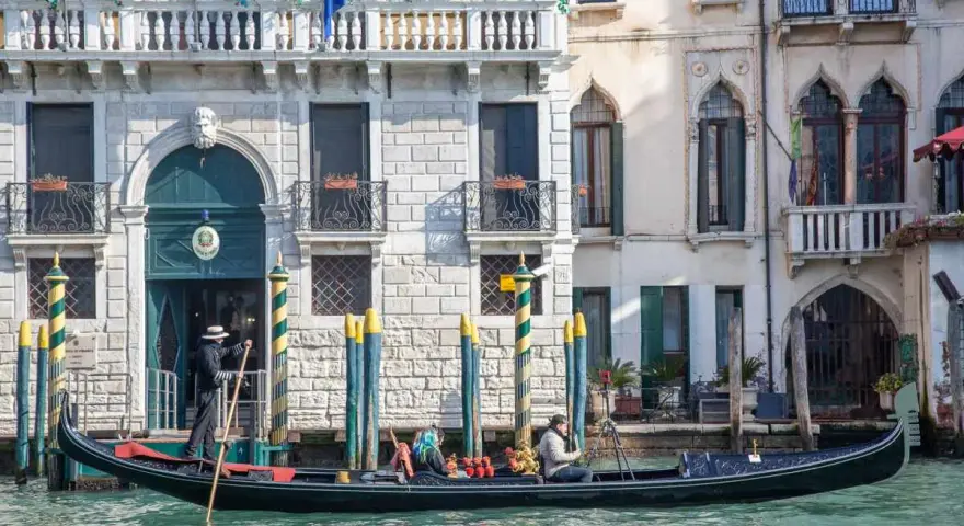 Gondola con gondoliere e passeggeri naviga lungo un canale a Venezia. Esplorare Venezia a piedi è un'esperienza, ma una gondola offre una prospettiva unica.