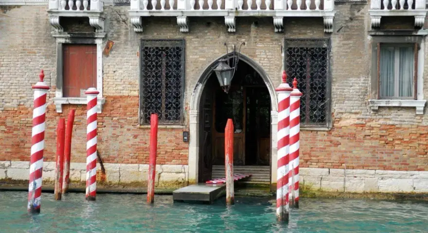 I pali di Venezia, chiamati bricole, segnano il canale davanti a un palazzo storico.