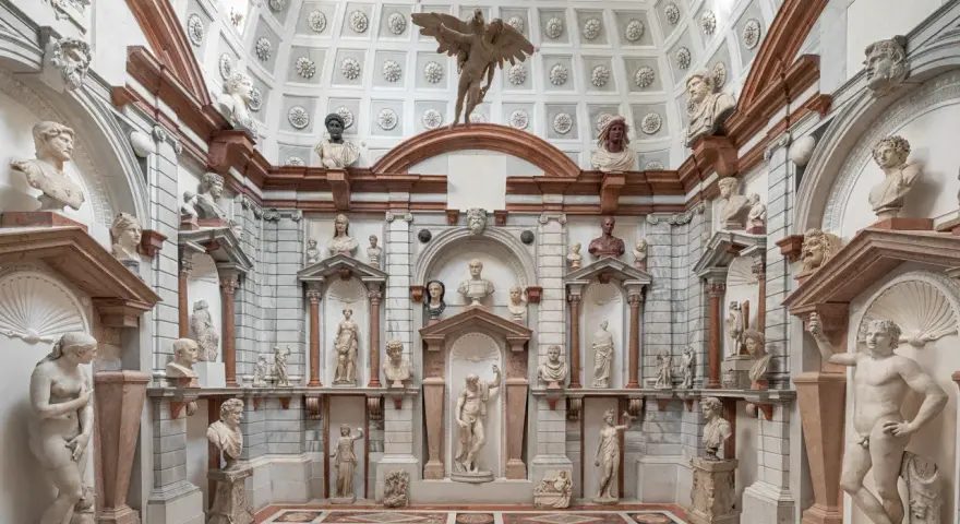 Interno del Palazzo Grimani a Venezia, un tripudio di sculture classiche e busti antichi che adornano nicchie e mensole, creando un'atmosfera di maestosa antichità.