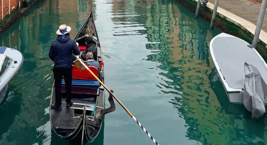 Gondola con gondoliere e passeggeri naviga in un canale veneziano vicino al park sant'andrea venezia.