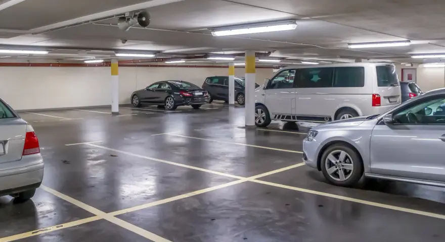Parcheggio sotterraneo con diverse auto, tra cui un furgone bianco e una berlina nera. Un'auto argentata è in primo piano. Questo è l'ingresso a Venezia per chi arriva in auto.