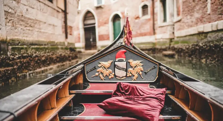 Gondola con cuscino rosso, pronta per un giro romantico a Venezia, città dell'amore.