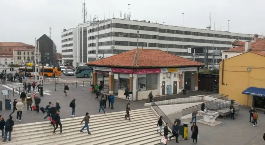 Persone attraversano le scale a Piazzale Roma, vicino a una fermata del vaporetto.
