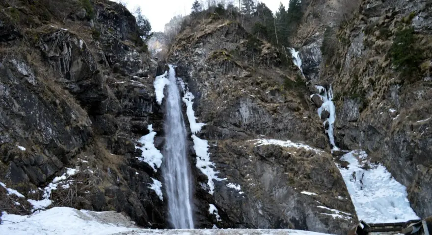Cascate in Veneto, con rocce innevate e ghiaccio che scende lungo i fianchi della montagna.
