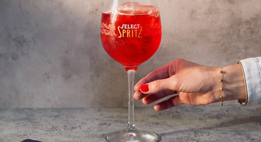 Un bicchiere di Spritz Select, con oliva e ghiaccio, pronto per essere gustato. Un tocco di Venezia in ogni sorso.