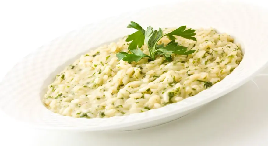 Risotto cremoso con prezzemolo, un piatto che evoca i sapori del mare di Venezia.
