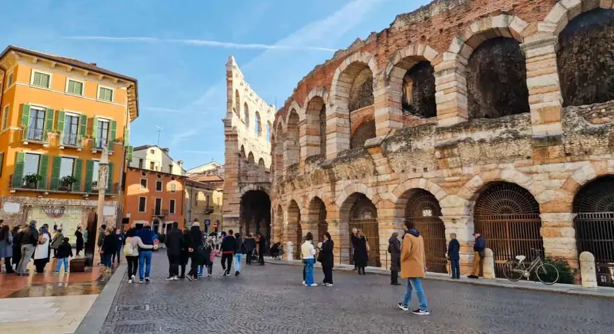 L'arena di Verona interno, con la sua maestosa struttura in pietra e archi, fa da sfondo a una piazza animata da turisti.
