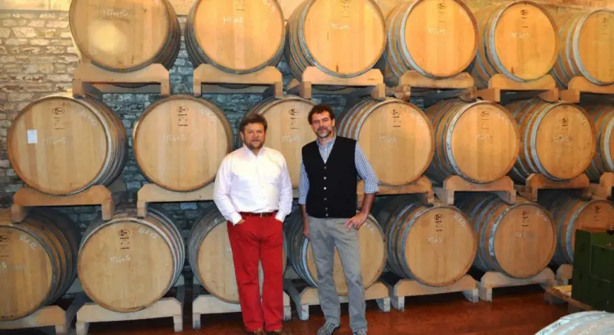 Due uomini in una cantina con botti di legno, simbolo delle migliori cantine dei Colli Euganei.
