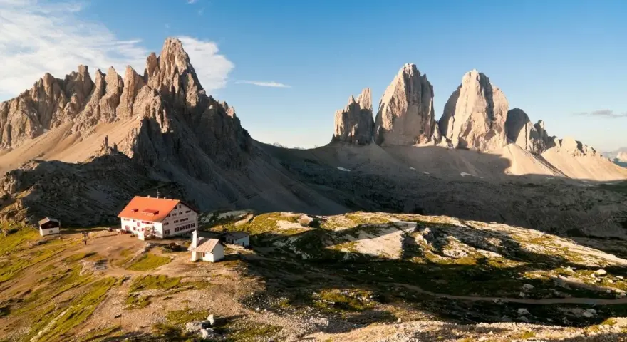 Rifugio con tetto rosso e montagne imponenti, un'oasi di pace tra i rifugi Dolomiti Bellunesi facili, ideale per un'escursione panoramica.