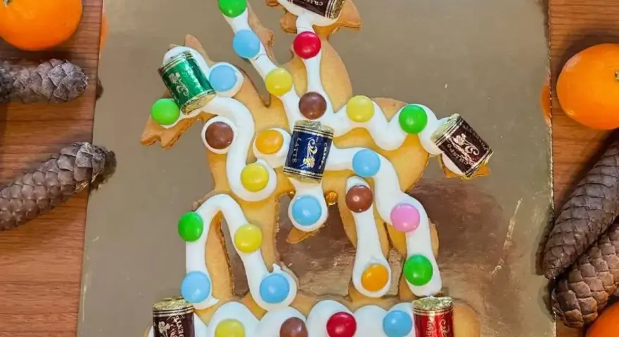 San Martino, dolce veneziano: biscotto decorato con glassa bianca, caramelle colorate e piccoli cioccolatini a forma di botte, su sfondo dorato.