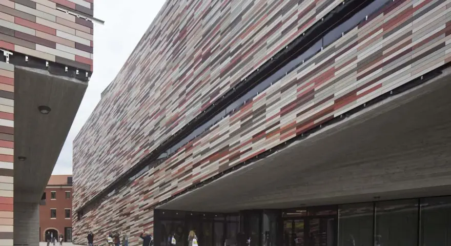 Il museo M9 a Mestre, con la sua facciata a listelli colorati, accoglie visitatori sotto un'imponente pensilina in cemento.
