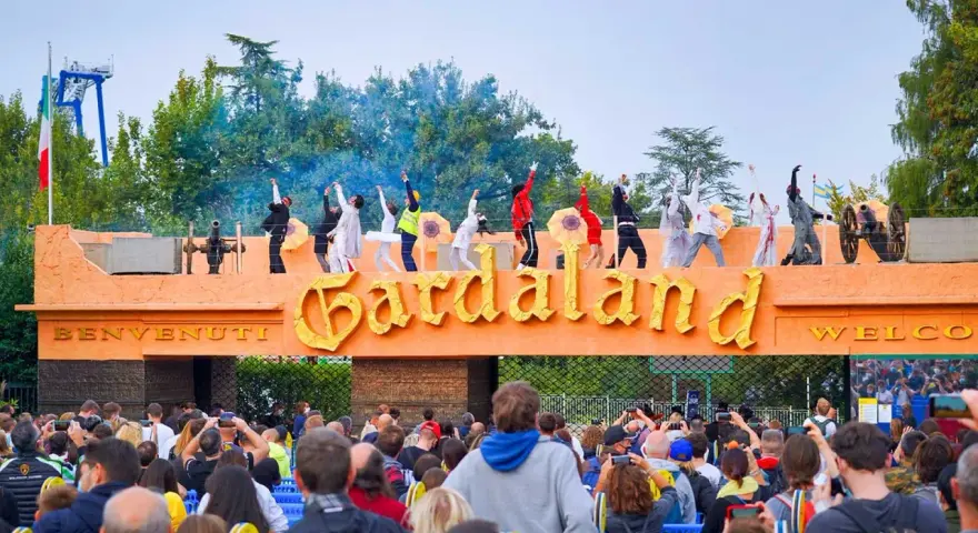 L'emozione di arrivare da Verona a Gardaland: artisti danzano sull'ingresso mentre la folla attende l'avventura.