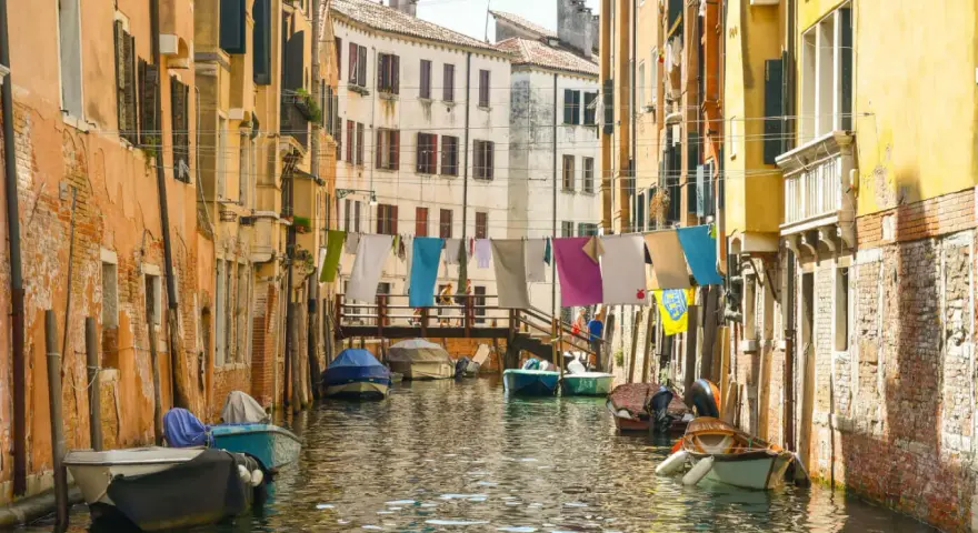 Angoli nascosti di Venezia: un canale tranquillo con barche ormeggiate e panni stesi ad asciugare tra case colorate.