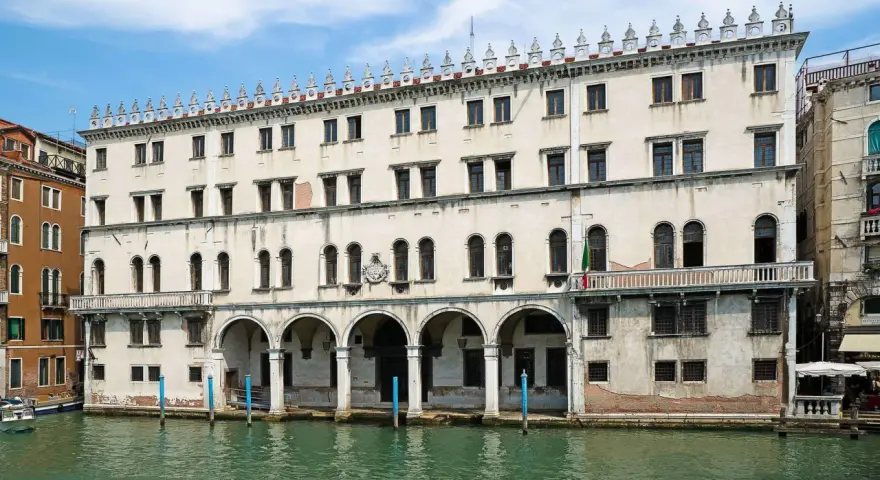Palazzo sul Canal Grande, un tempo sede dei mercanti tedeschi, con le sue arcate e finestre che riflettono l'acqua di Venezia.