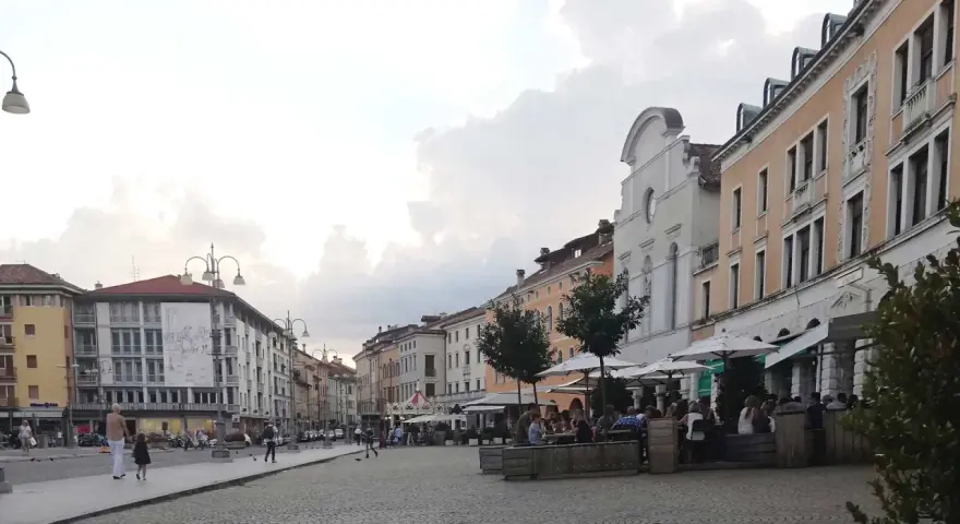 Passeggiata serale in piazza a Belluno, cosa vedere: palazzi storici, locali all'aperto e gente che si gode la serata.