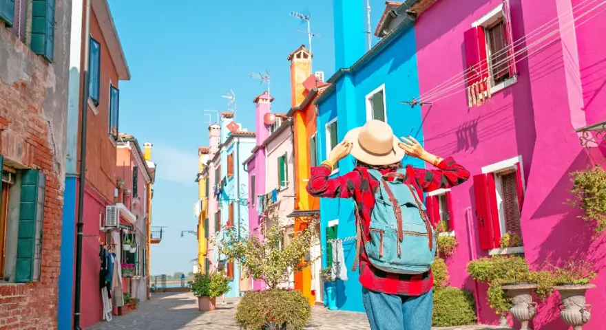 Una turista ammira le case colorate di Burano, un'isola raggiungibile con i traghetti da Chioggia.