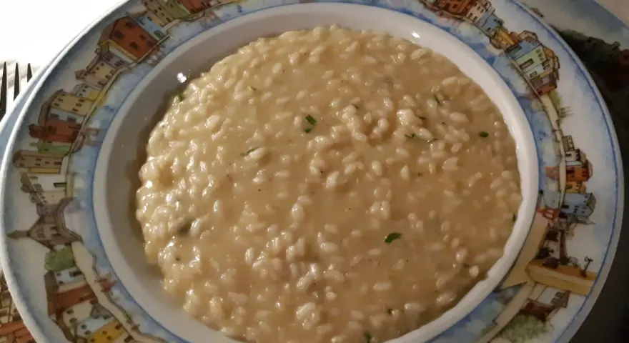 Un cremoso risotto di go Burano, servito in un piatto decorato con le case colorate dell'isola.