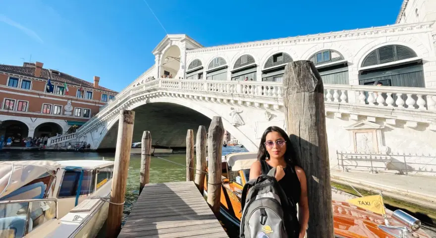 Una splendida giornata a Venezia, con la giovane donna che posa con il suo zaino davanti al Ponte di Rialto e ai taxi d'acqua.