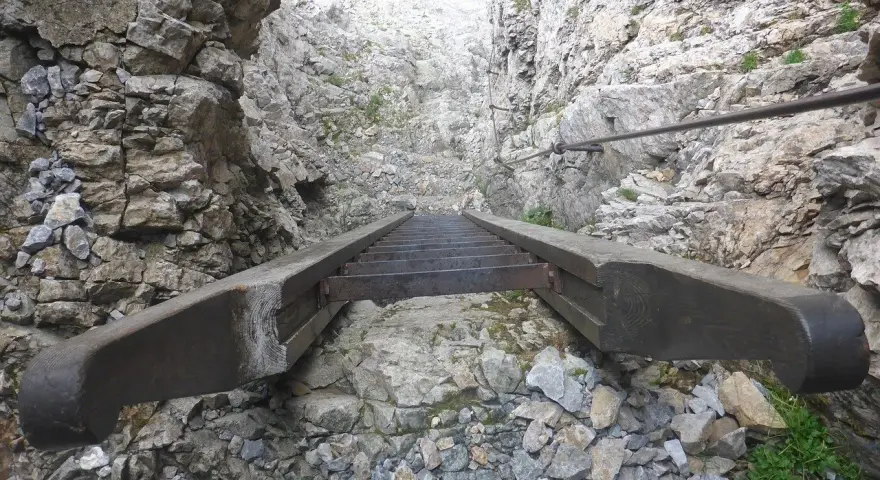 Scalinata in metallo e legno su roccia, parte di un percorso attrezzato, tipico delle ferrate in Veneto.