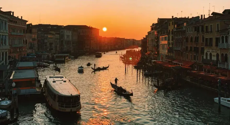 Tramonto sul Canal Grande, con gondole e vaporetti. Un'immagine da uno dei tanti punti panoramici di Venezia, con il sole che illumina l'acqua.