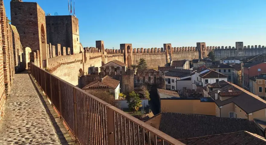 Passeggiata sulle mura della **cittadella** di Padova, con vista sui tetti e le torri medievali sotto un cielo azzurro.
