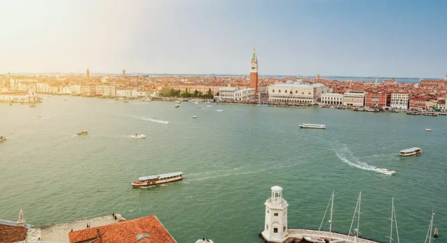 Vista aerea di Venezia con il Canal Grande, imbarcazioni e la famosa arte della città sullo sfondo.