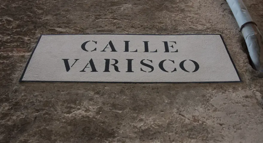 Targa in pietra con scritta "CALLE VARISCO" a Venezia, incastonata in un muro grezzo.