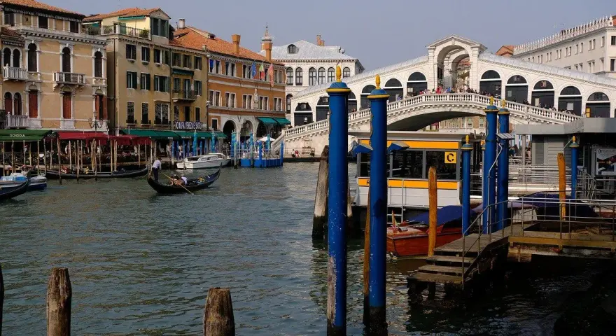 Venice canal with gondola, Rialto Bridge, and buildings.