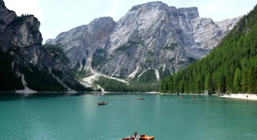 Lago turchese con barche a remi e maestose montagne veneto sullo sfondo.
