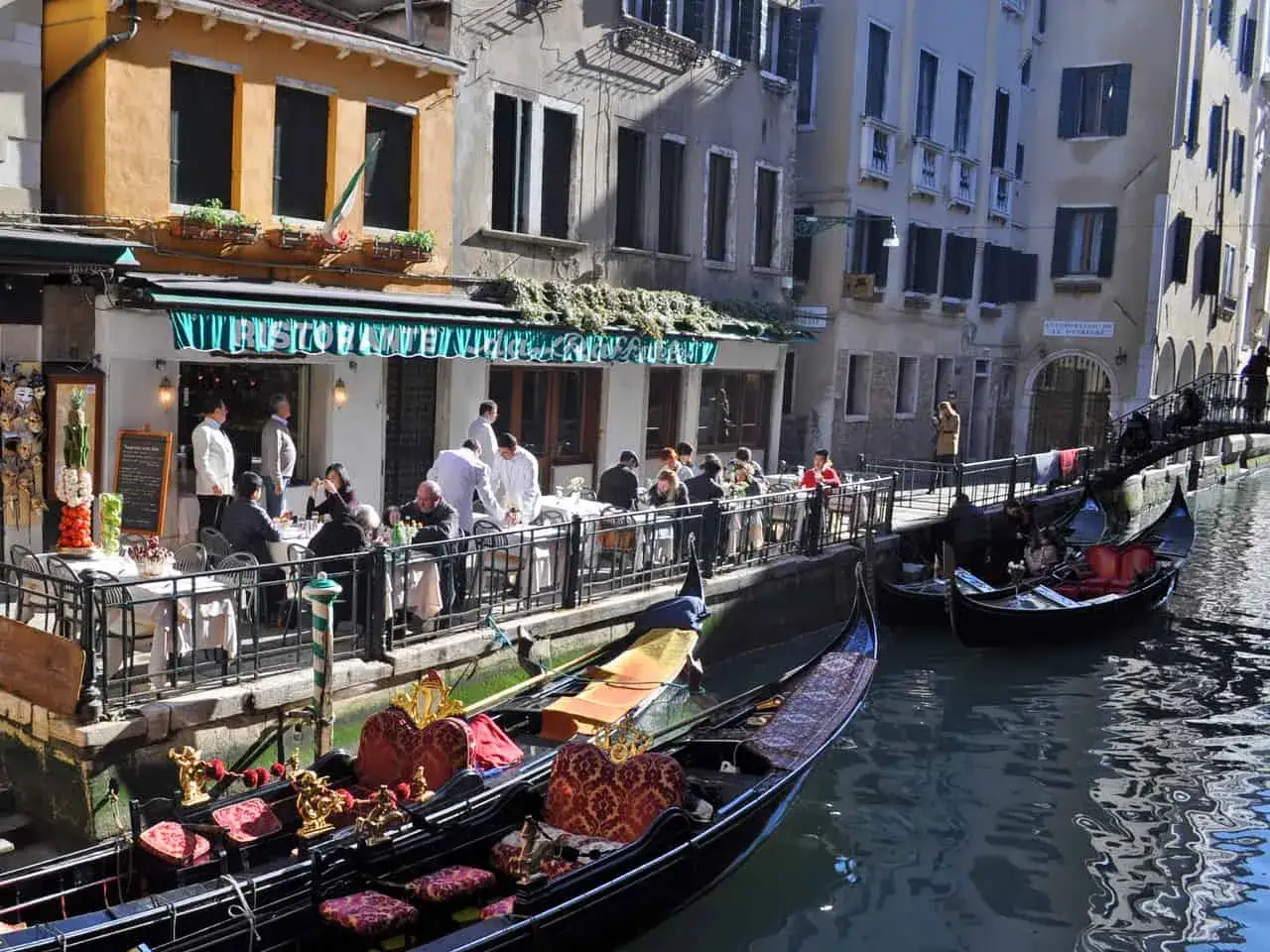 Gondole ormeggiate vicino a un ristorante con tavoli all'aperto, un'ottima scelta tra i migliori ristoranti di Venezia.