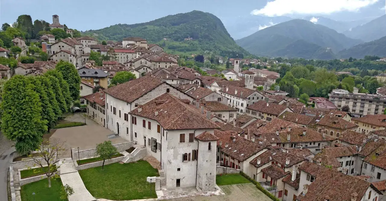 Panoramica di Feltre e dintorni, con tetti rossi e case storiche che si arrampicano sulle colline verdi.