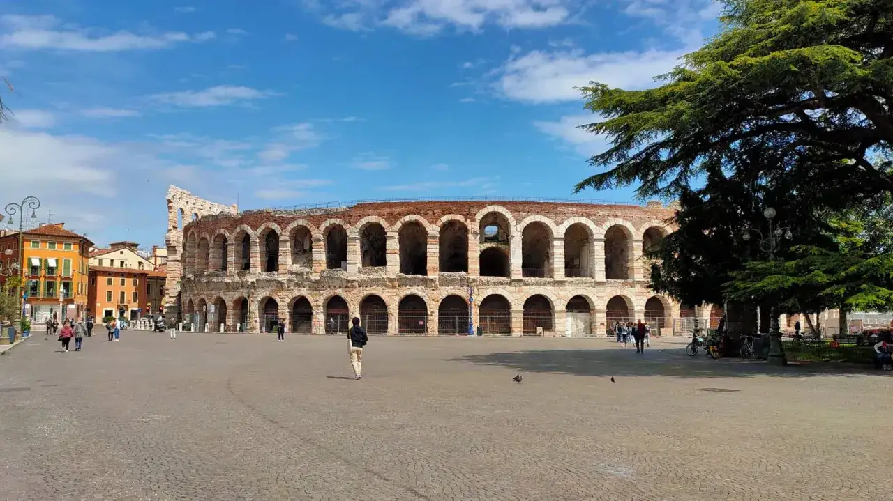 L'Arena di Verona, con i suoi quasi 2000 anni, domina la piazza. Un turista ammira la sua maestosit&agrave;.