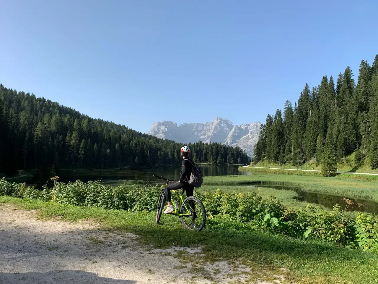 Ciclista ammira il panorama sul lago e le montagne lungo la ciclabile Auronzo Misurina.