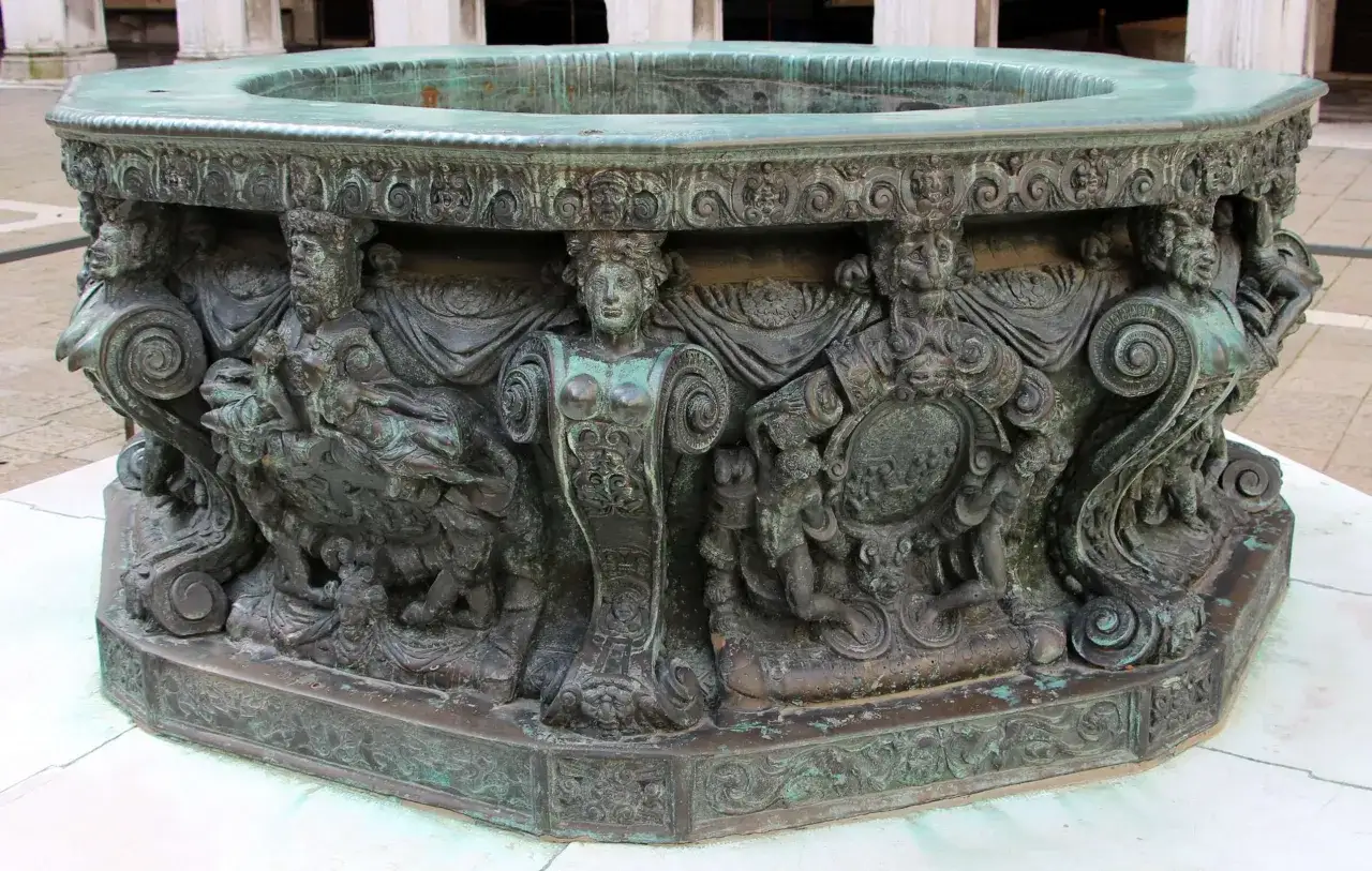 Antico pozzo a Venezia, con decorazioni scultoree in bronzo raffiguranti figure mitologiche e scene allegoriche.