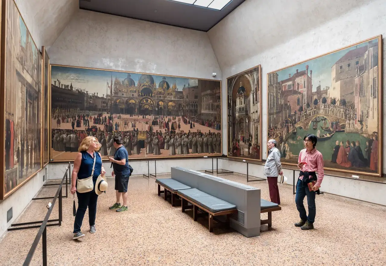 Visitanti ammirano grandi dipinti storici in uno dei musei d'arte a Venezia.