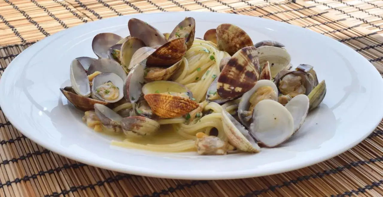 Spaghetti alle vongole, un classico dei ristoranti di pesce a Caorle, serviti su un piatto bianco.