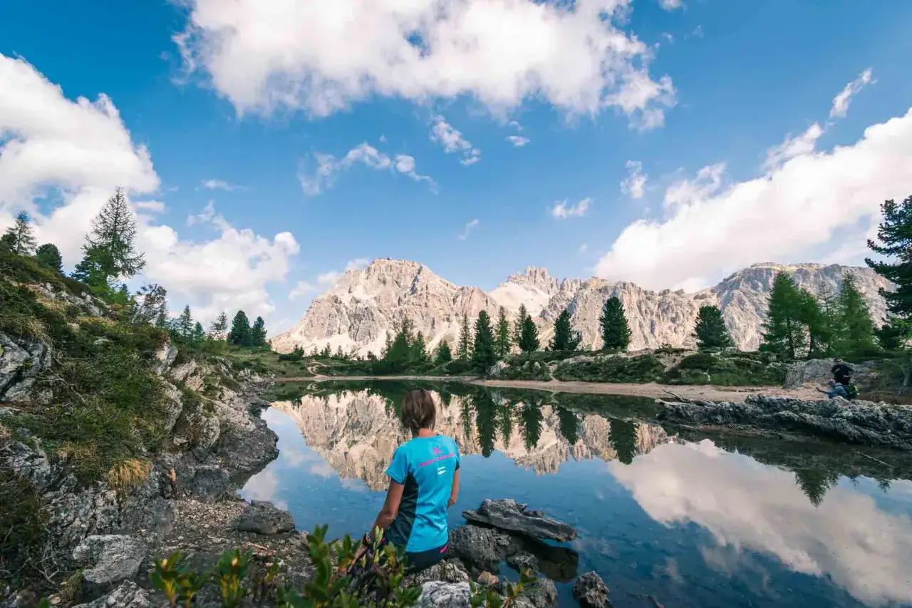 Donna ammira il riflesso delle montagne nel lago di Limedes.
