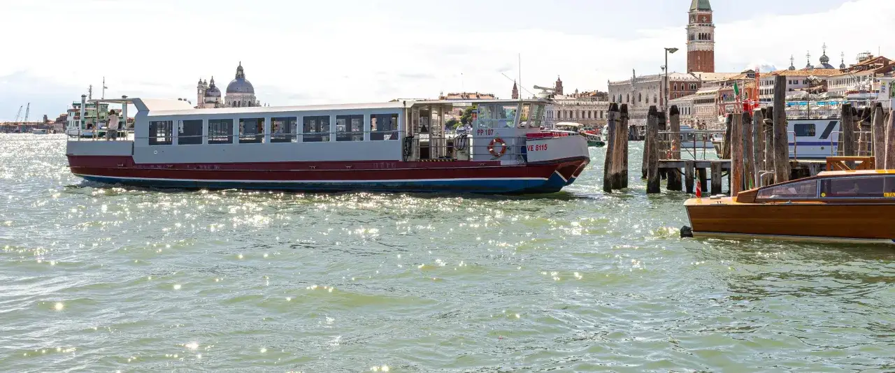 Un vaporetto di Venezia solca le acque scintillanti, con la colorata Burano sullo sfondo.