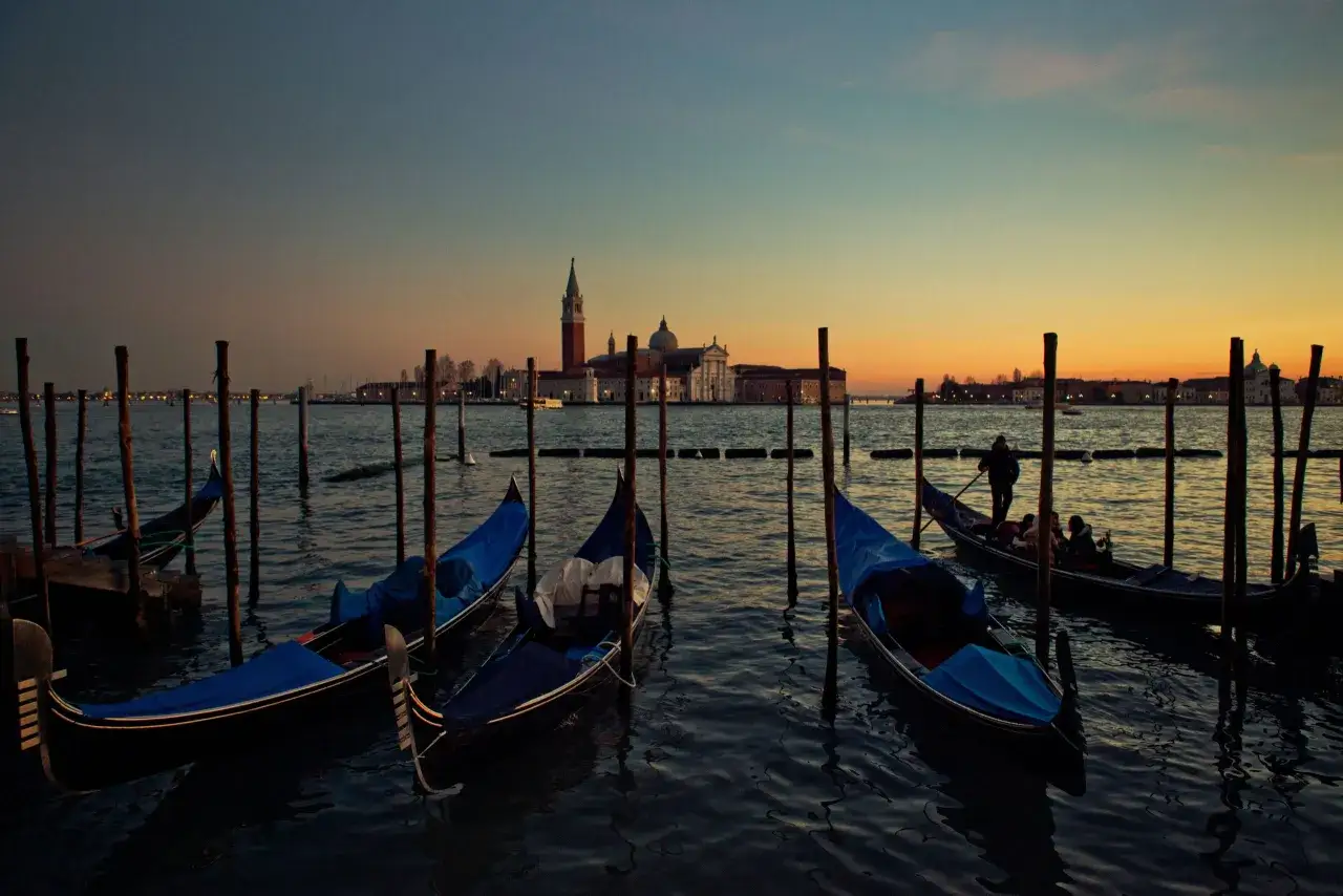 Gondole ormeggiate al tramonto, con la Basilica di San Giorgio Maggiore sullo sfondo. Un'atmosfera da sogno, perfetta per scoprire i posti romantici Venezia.