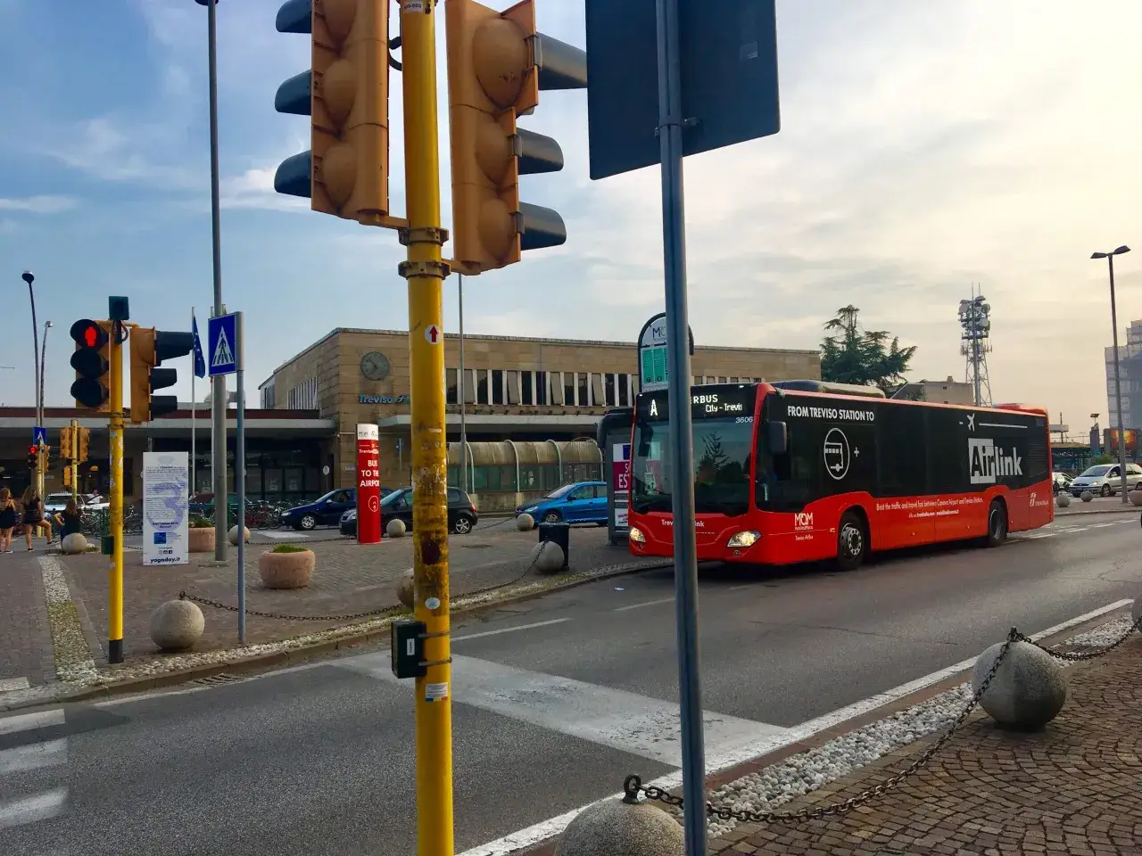 Bus Airlink rosso da Treviso Station a Padova, con segnali stradali e semafori in primo piano.