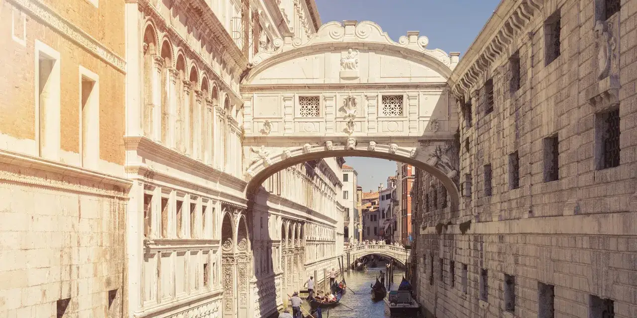 Il ponte dei sospiri interno visto da un canale veneziano, con gondole e palazzi storici.
