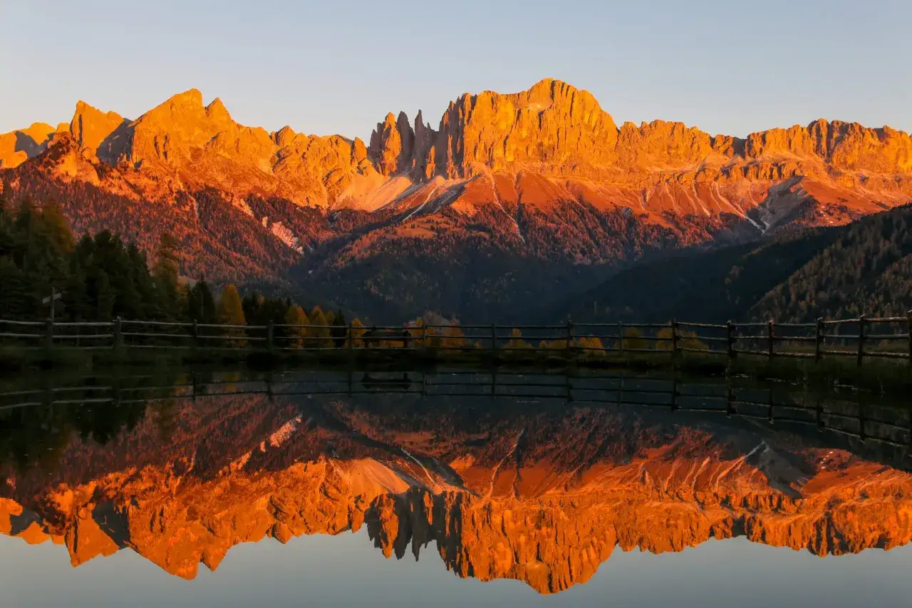 Le Dolomiti Rosse illuminate dal tramonto si specchiano in un lago tranquillo, creando un paesaggio mozzafiato.