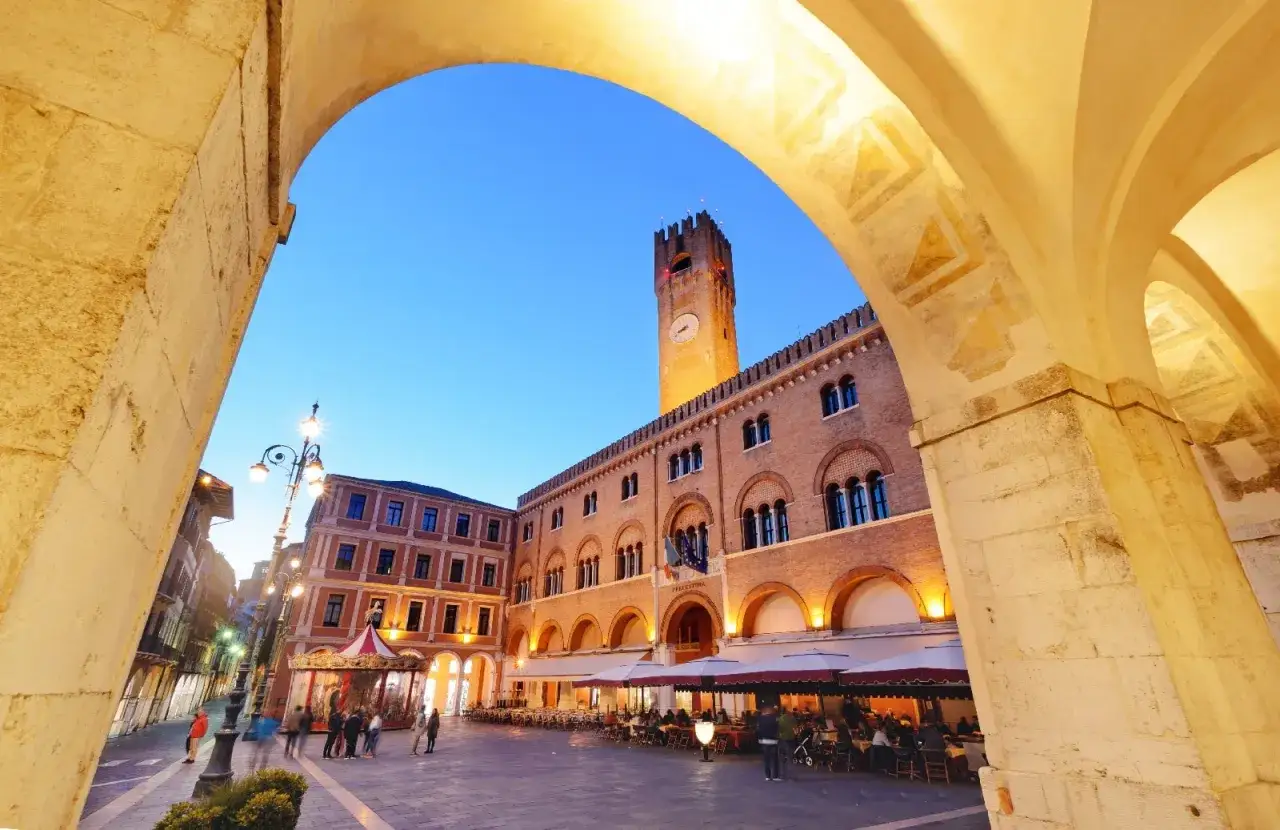 Piazza dei Signori a Treviso, con il Palazzo dei Trecento e la torre civica illuminati al crepuscolo. Un luogo incantevole da scoprire tra le cose da vedere a Treviso.